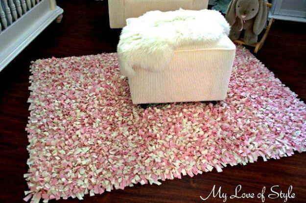 Pink and ivory shag DIY rag rug knotted through a rug pad, with a pale striped nursery ottoman standing on it
