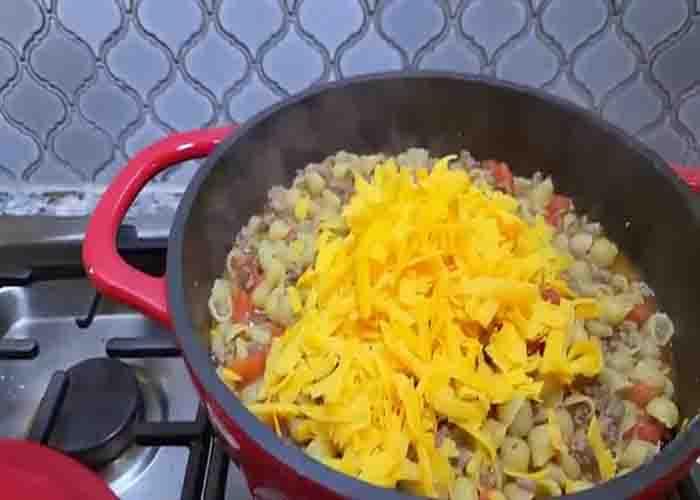 Adding shredded cheese in the shells and beef dish