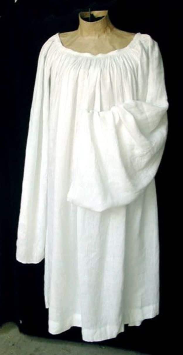 Long white linen Italian chemise with full gathered sleeves, displayed on a dress form against black