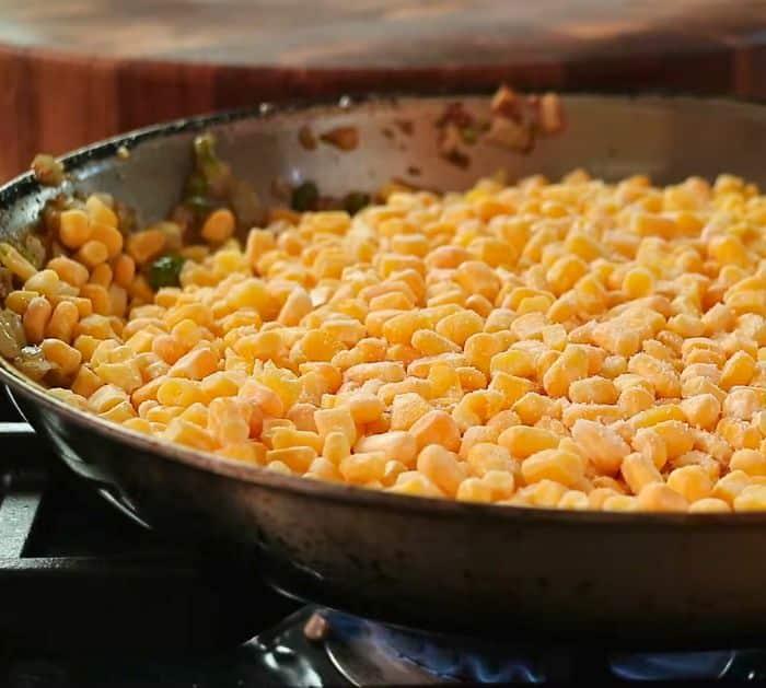 sauteed vegetables with frozen corn in a pan over heat
