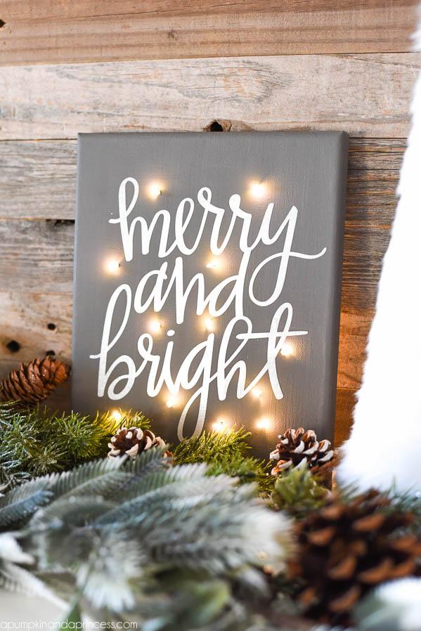 Gray painted canvas with white lettering and tiny twinkle lights pushed through the front glowing in a dim room