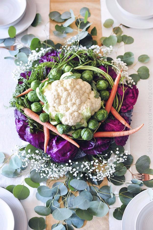 Thanksgiving food centerpiece of raw vegetables layered on parchment around a whole cauliflower with baby's breath