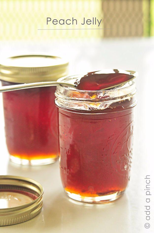 Homemade peach jelly in canning jars, clear golden and set, with fresh ripe peaches on a wooden board