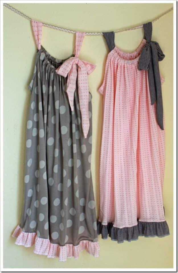 Two girls nightgowns in gray polka dot and pale pink, with ruffled hems and fabric bows, hanging from a ribbon
