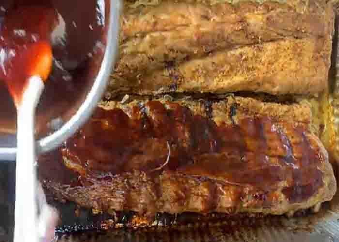 Brushing the baby back ribs with grape jelly sauce