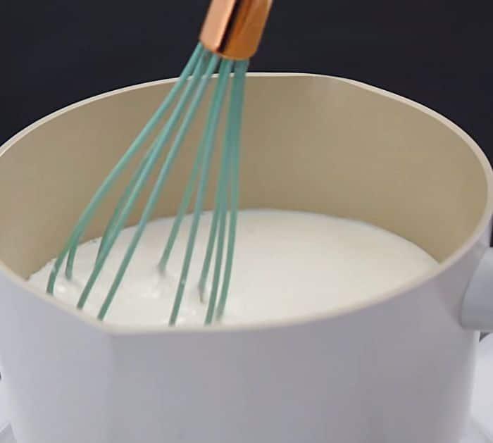 Mixing milk mixture in a small pot using a whisk