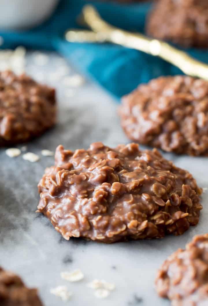 Chocolate peanut butter no bake cookies, dark oat drop cookies on pale marble with a teal cloth behind them