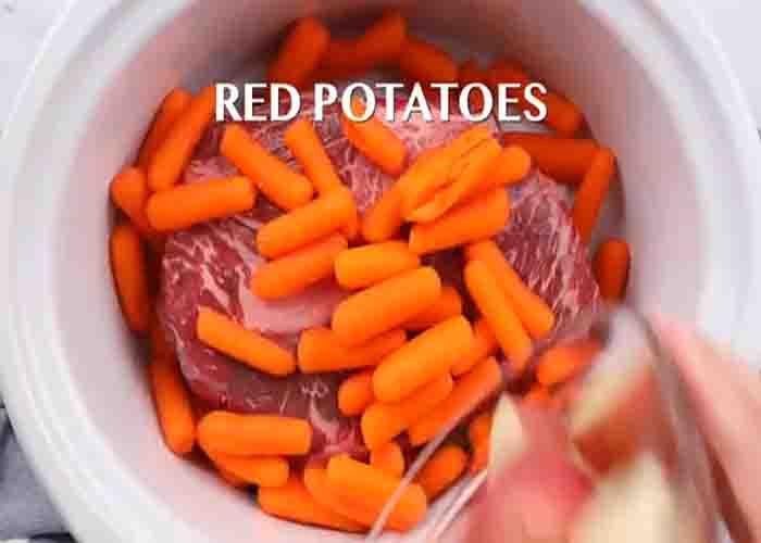 Adding the coca cola pot roast ingredients in the slow cooker