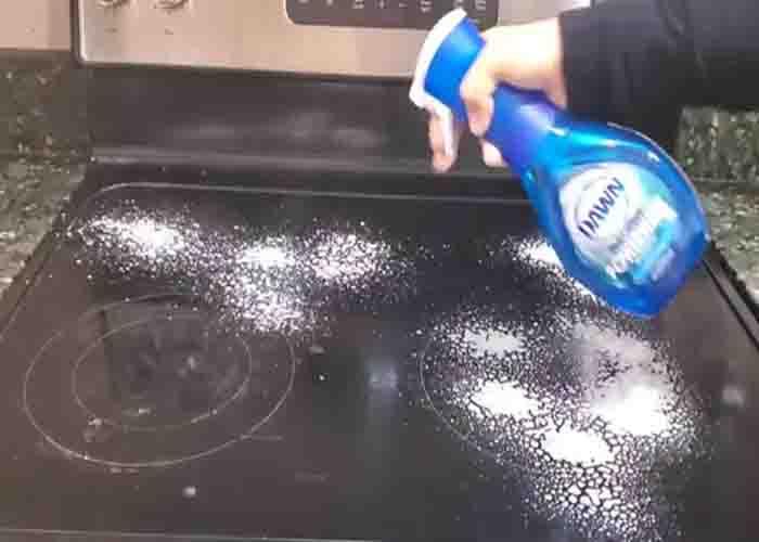 Spraying Dawn dish soap over the glass stovetop