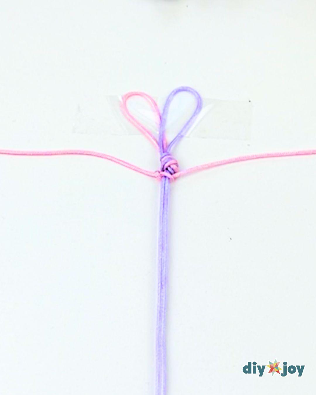 An easy macrame bracelet resting on a table beside scissors and measuring tape, the only tools the project needs