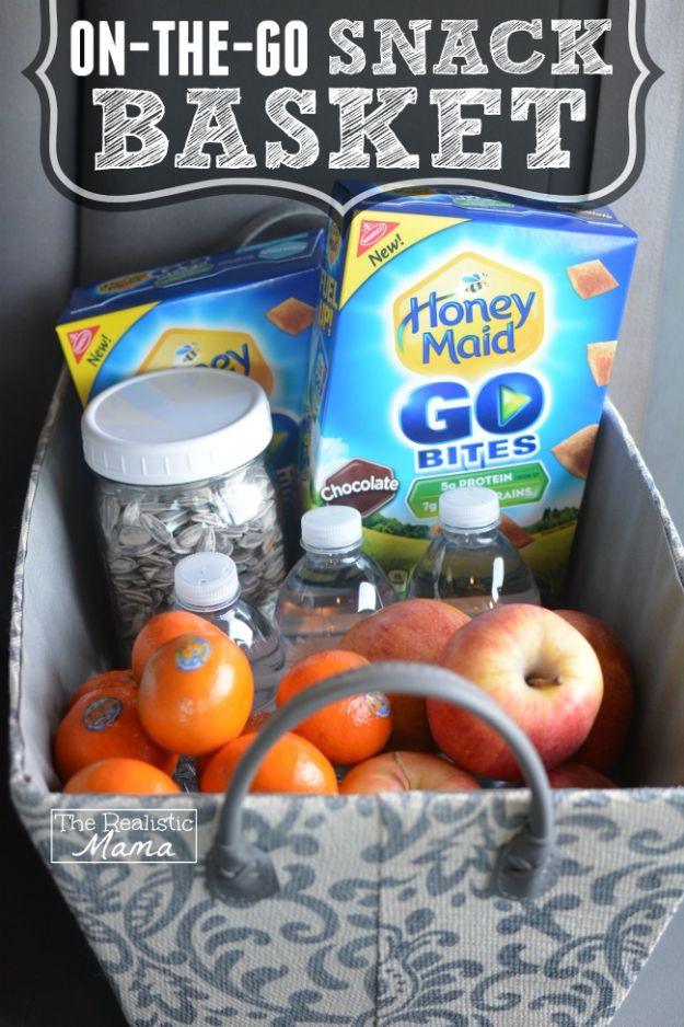 On the go snack basket, a gray fabric basket with a handle holding apples, clementines, water, seeds and a snack box