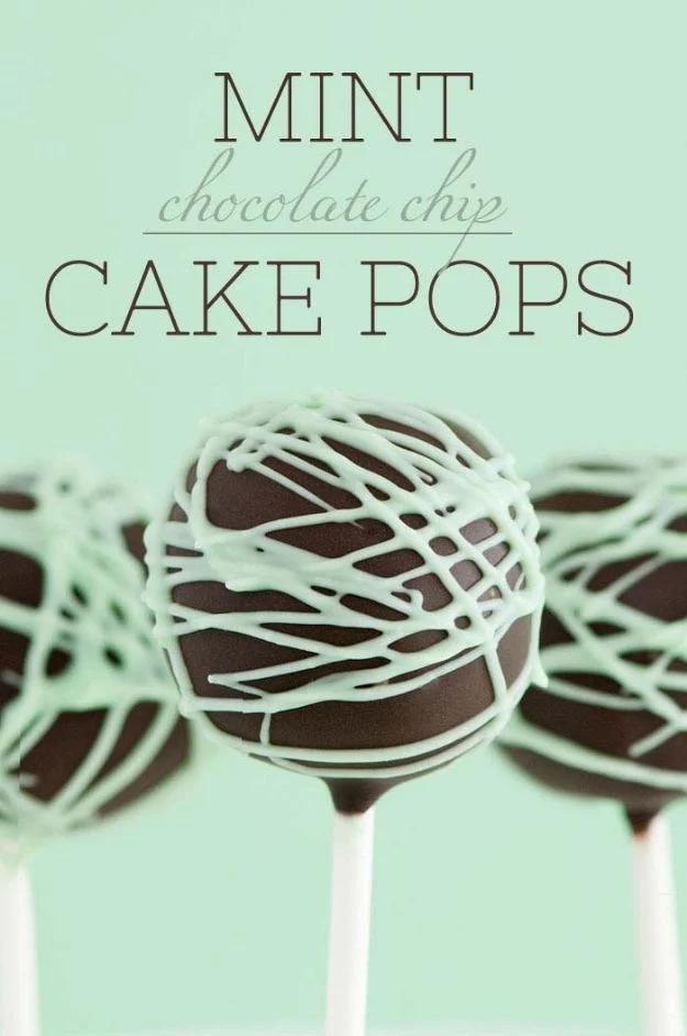 Mint chocolate cake pops with mini chocolate chips inside, dipped dark and drizzled mint green candy, cooling on a rack