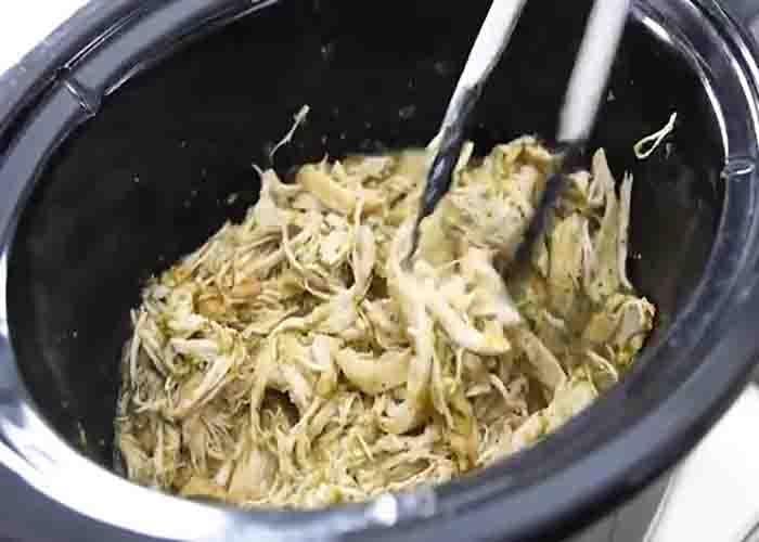 Shredding the chicken and mixing it with the salsa verde