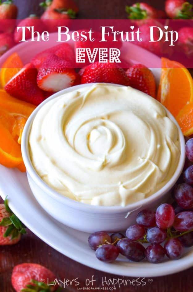 Best fruit dip in a bowl beside a platter of strawberries, apple slices and grapes ready for dipping