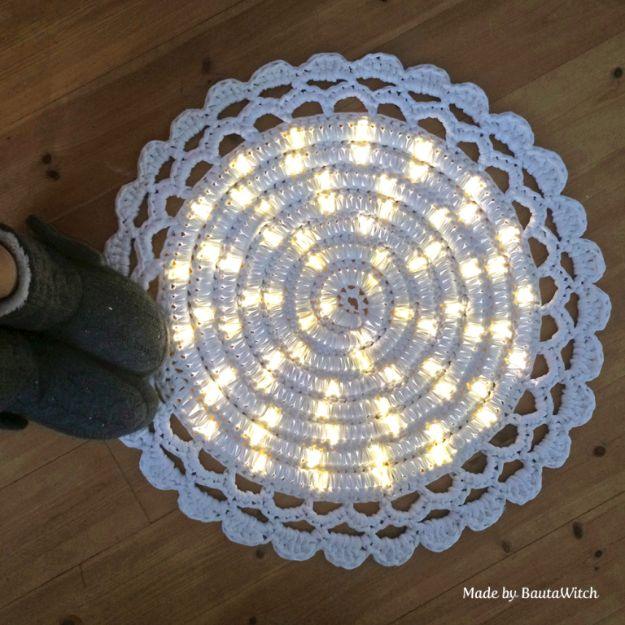 Round white crocheted DIY rug with a glowing light rope worked inside it, a slippered foot at the edge of frame
