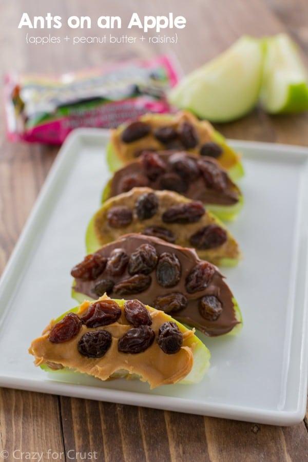Ants on an apple, green apple wedges spread with peanut butter and topped with neat rows of dark raisins