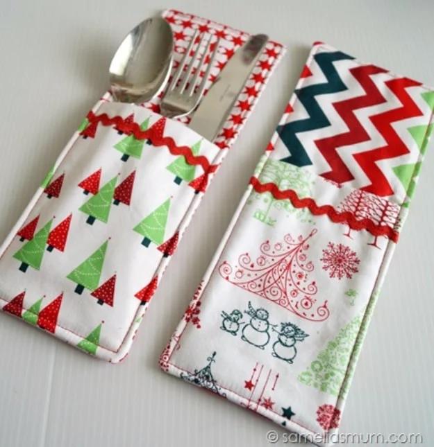 Two Christmas print cutlery pockets on a white surface, one holding a spoon, fork and knife, trimmed with ric rac