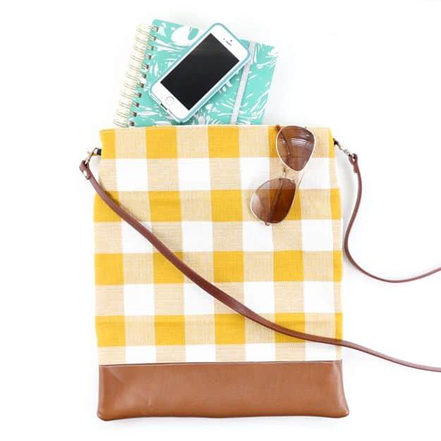 A yellow plaid crossbody bag made from a kitchen towel, with a faux leather strap, hanging on a white wall hook.