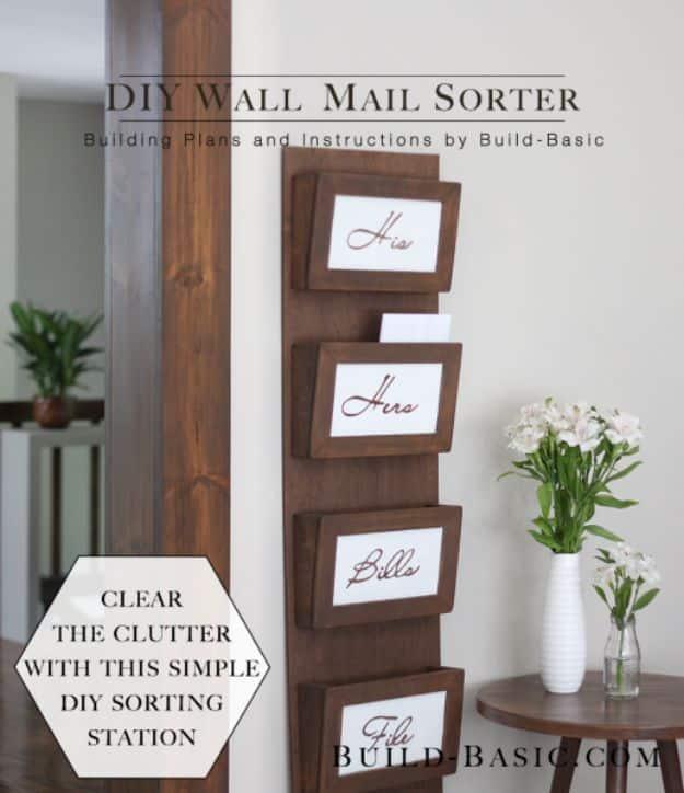 Tall dark stained wall mail sorter with four labelled pockets mounted on a white wall beside a side table and flowers