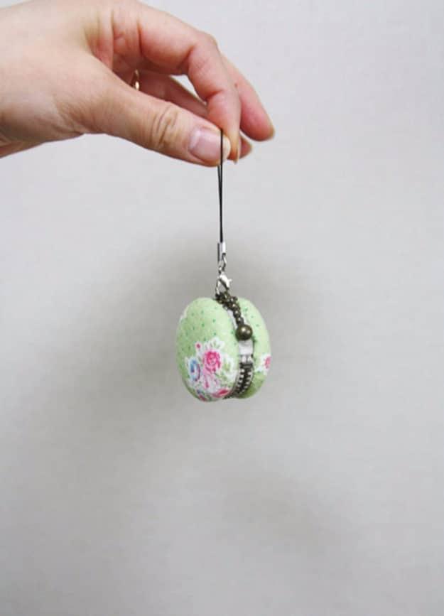 Small round macaron shaped coin purse in pale green rosebud print with a beaded rim, hanging from a wrist strap