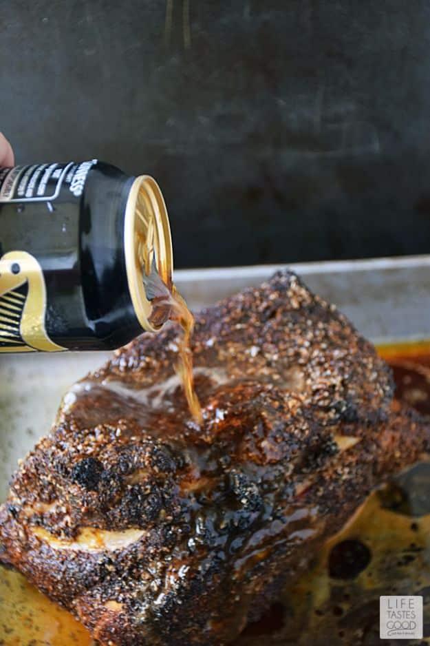 Beer braised pulled pork, a dark crusted pork roast in a pan with Guinness being poured over the top