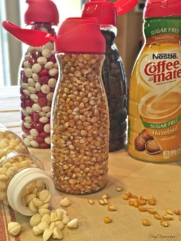 Clear coffee creamer bottles with red flip tops refilled with popcorn kernels, nuts and white chocolate chips