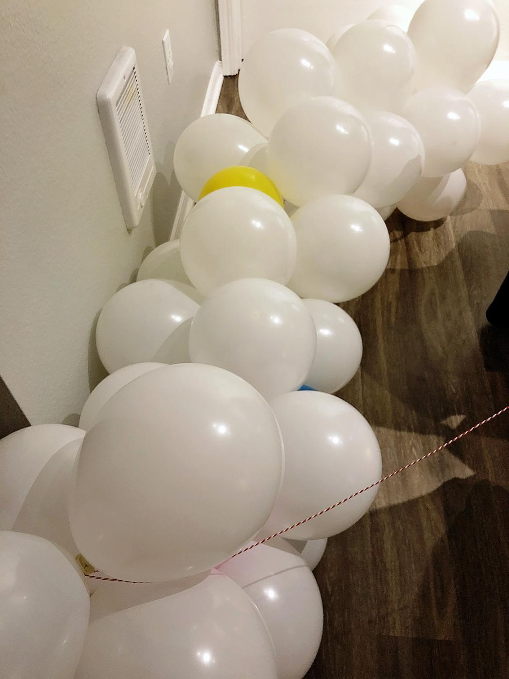 Christmas tree wrapped in a spiral garland of white and pastel balloons in three sizes instead of ornaments
