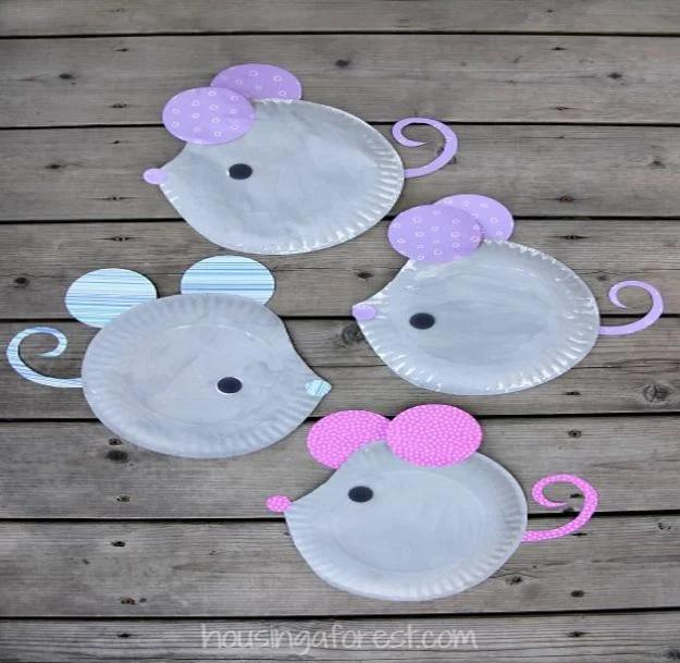 Three gray paper plate mice with patterned paper ears, black noses and curled paper tails, arranged on weathered gray wood