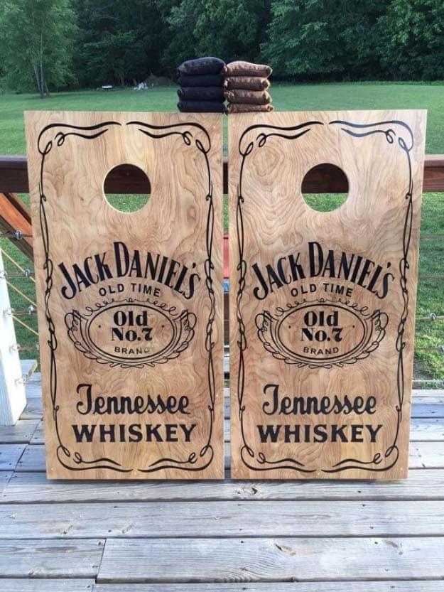 Jack Daniels stenciled cornhole boards in stained plywood with the Old No 7 label and bean bags on a deck