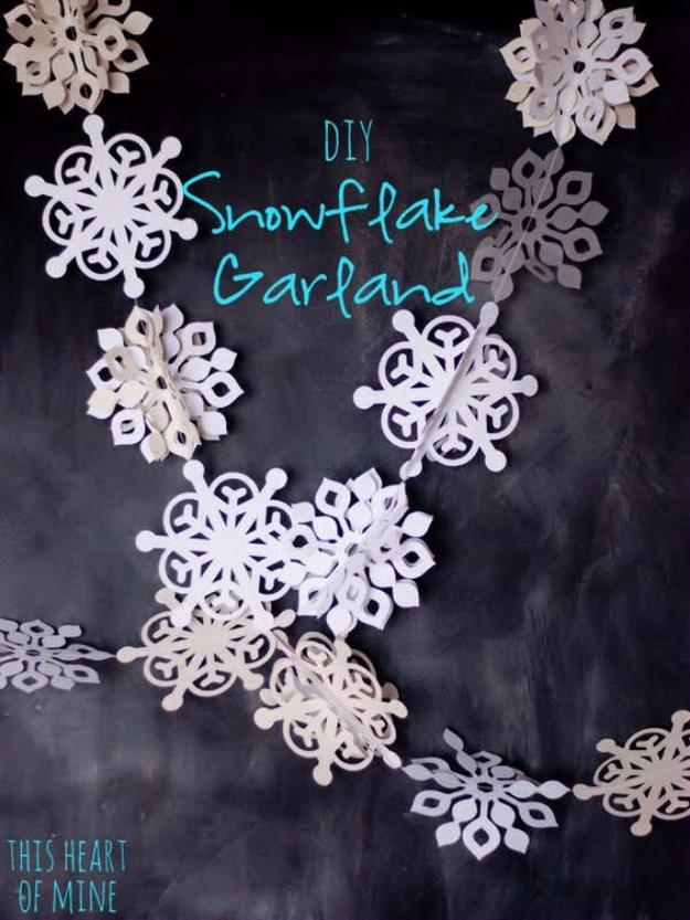 Paper snowflake garland in shades of white and gray sewn together, photographed against a chalkboard wall