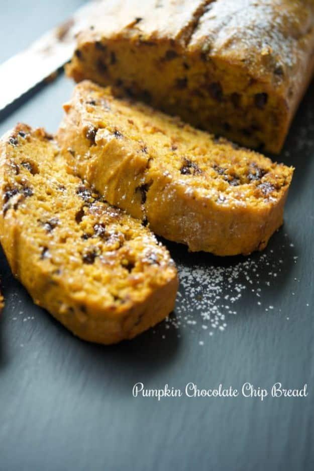 Pumpkin chocolate chip bread sliced on a dark slate board, chocolate chips scattered through the deep orange crumb