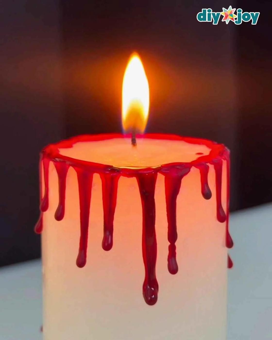 Step 3, a finished bloody candle with hardened red crayon blood drips ready for Halloween party decor and display.