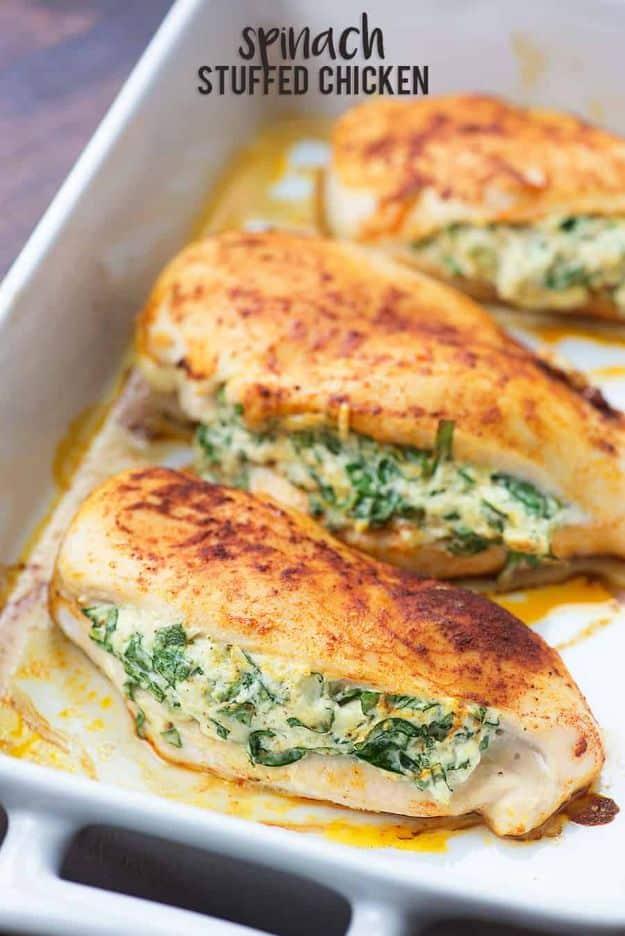 Spinach stuffed chicken breasts in a white baking dish, three breasts filled with spinach and cream cheese