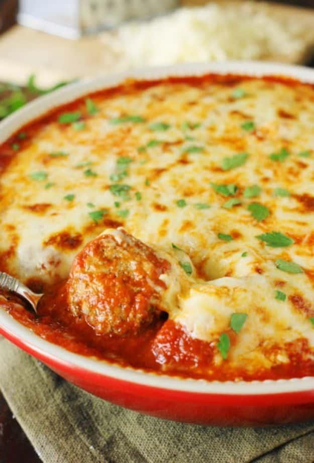 Easy meatball parmesan casserole with meatballs in marinara under browned melted mozzarella in a red dish