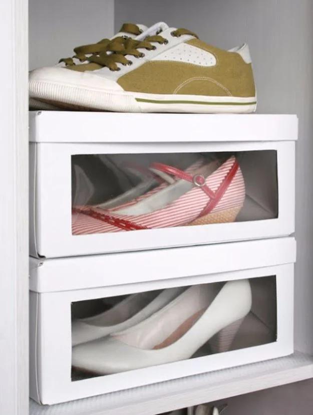 Two white shoe boxes stacked with clear plastic windows cut into the fronts showing the shoes stored inside