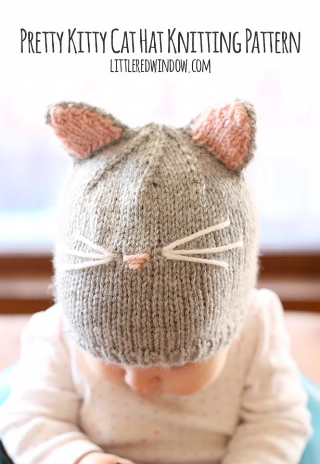 Grey knitted cat hat with pink lined ears, embroidered whiskers and a pink nose worn by a child looking down