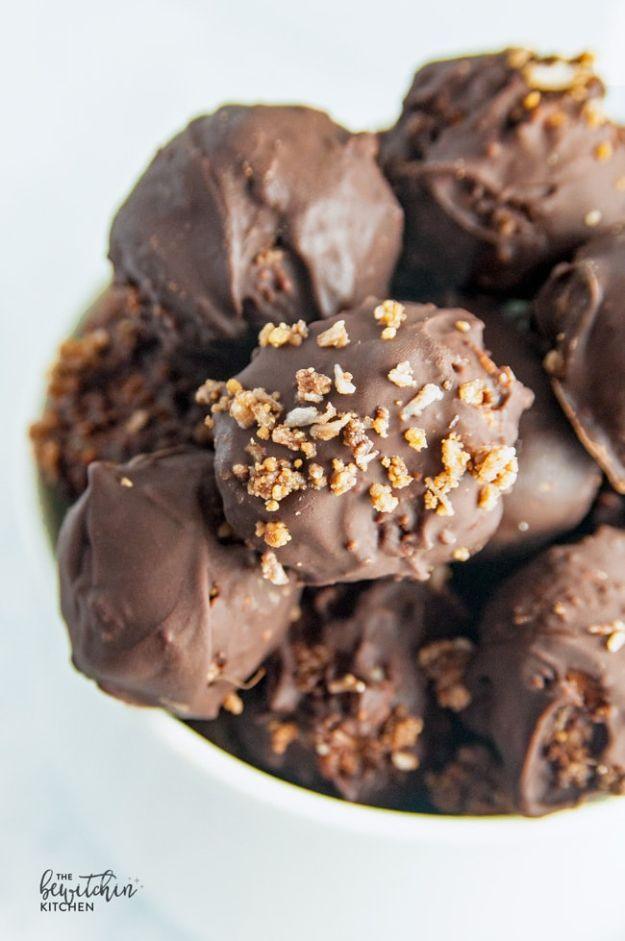 Nanaimo balls dipped in dark chocolate and scattered with coconut graham crumb, piled high in a white bowl
