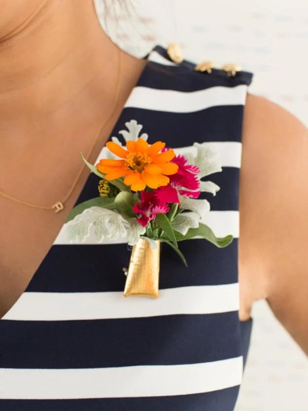 Cute floral brooch, a small gold vessel of fresh orange and pink blooms pinned to a navy striped dress