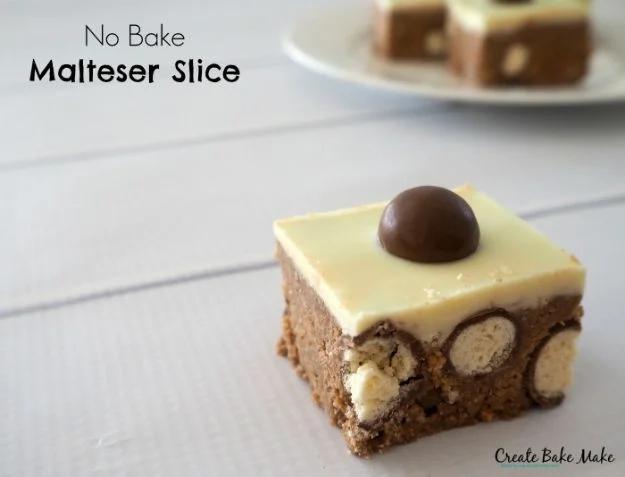 No bake Malteser slice cut into squares with whole Maltesers pressed into the chocolate topping, an easy no bake dessert