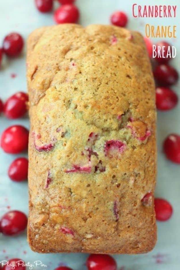 Cranberry orange bread loaf on a board surrounded by fresh red cranberries with a title overlay on the image