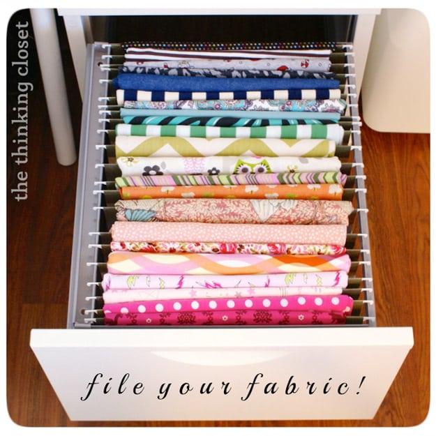 Folded fabric in rainbow order draped over file folders and stood upright in an open filing cabinet drawer