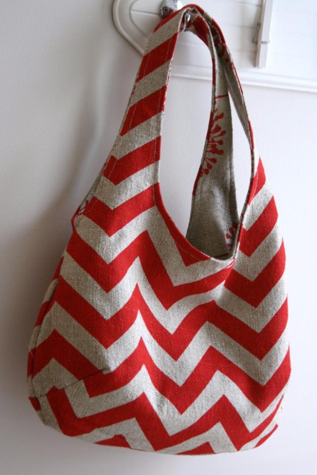 Slouchy shoulder bag in heavy red and oatmeal chevron fabric hanging on a white door knob with a coral lining