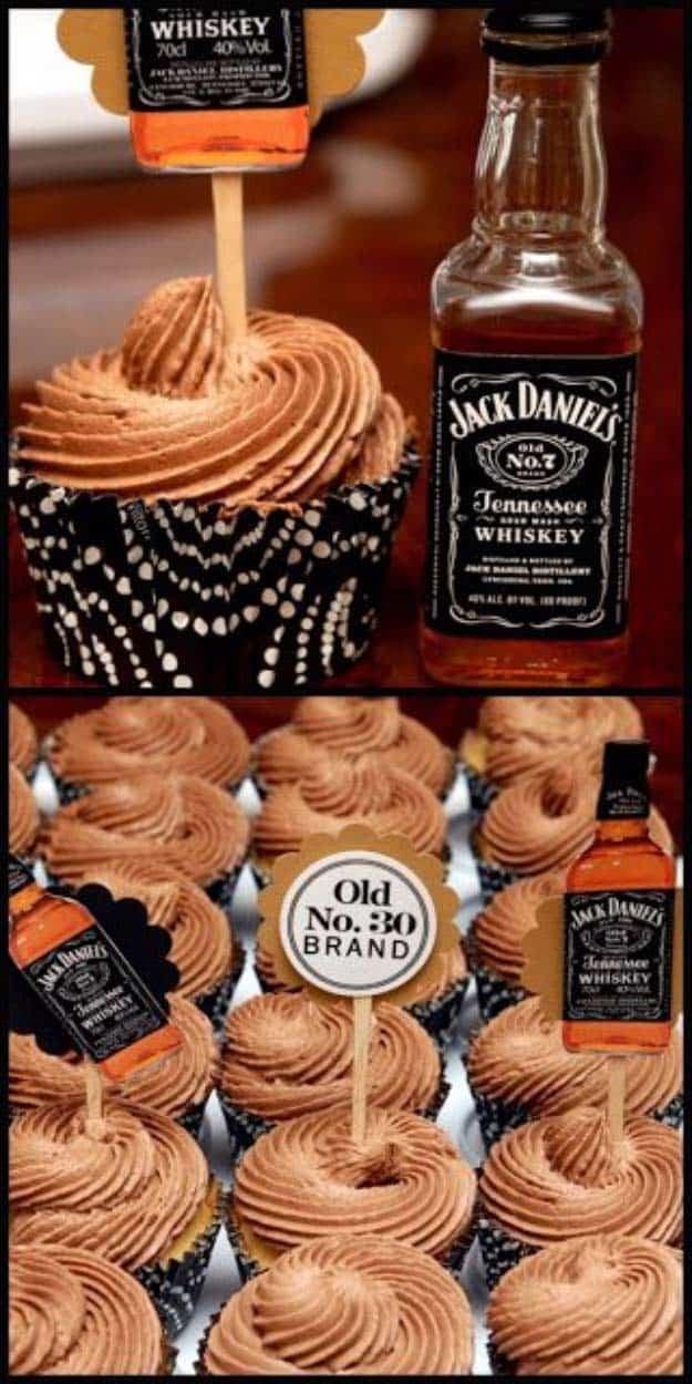 Jack Daniels cupcakes with swirled cocoa frosting in black spotted cases topped with miniature whiskey bottles