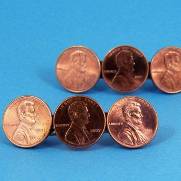 Six shiny copper pennies arranged on a bright blue background in the layout for a coin hair barrette