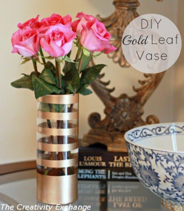 A clear glass vase with a crisp band of gold leaf across the bottom third, holding white blooms on a marble counter