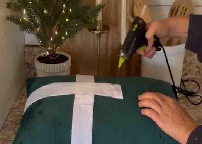 Hot gluing the ribbon to the velvet pillow cover for Christmas