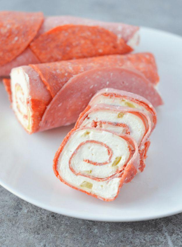 Keto pinwheels sliced into spirals of cream cheese and salami, arranged on a plain white plate with more slices