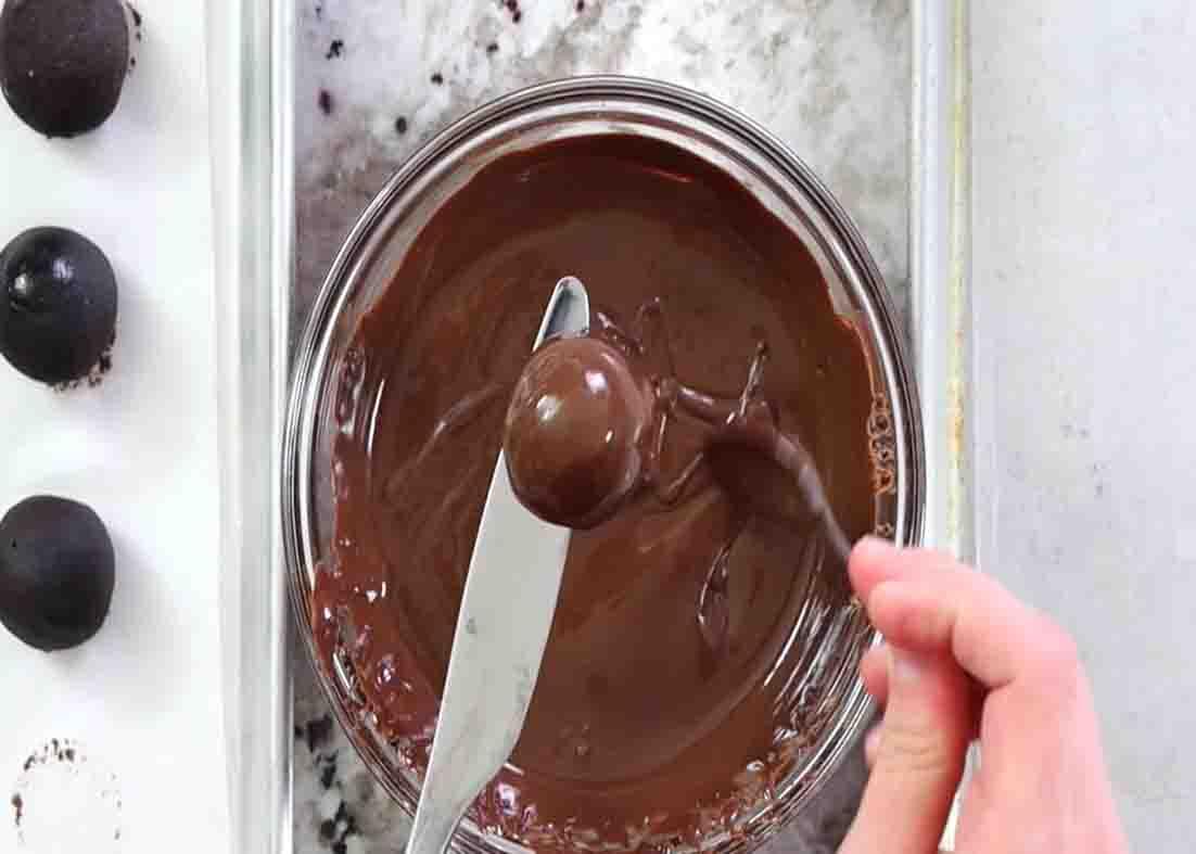 Coating the Oreo truffles with melted chocolate