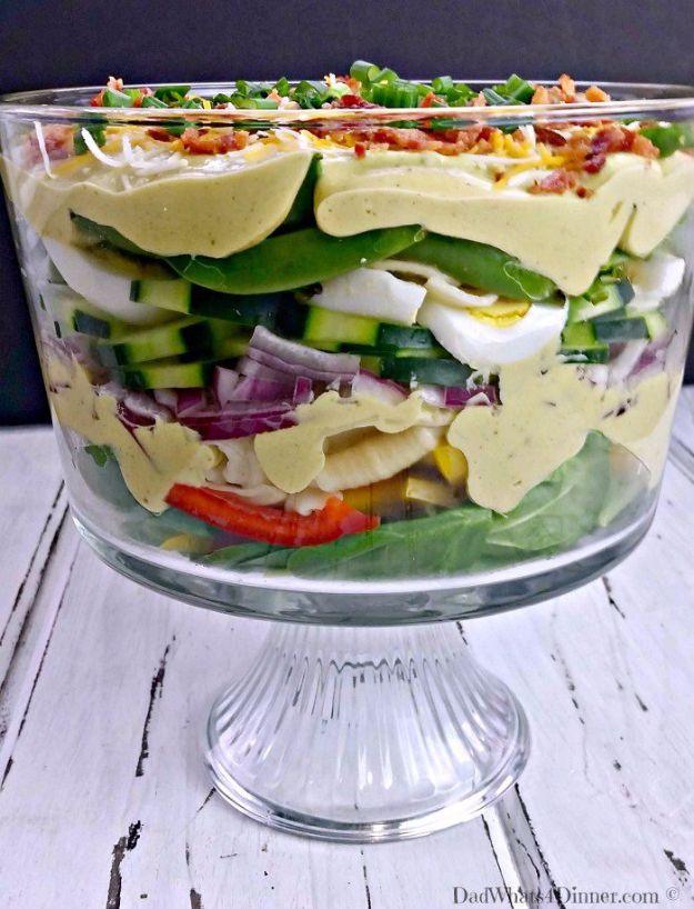 Creamy deviled egg layered pasta salad in a glass trifle bowl showing stripes of greens peppers egg and pasta