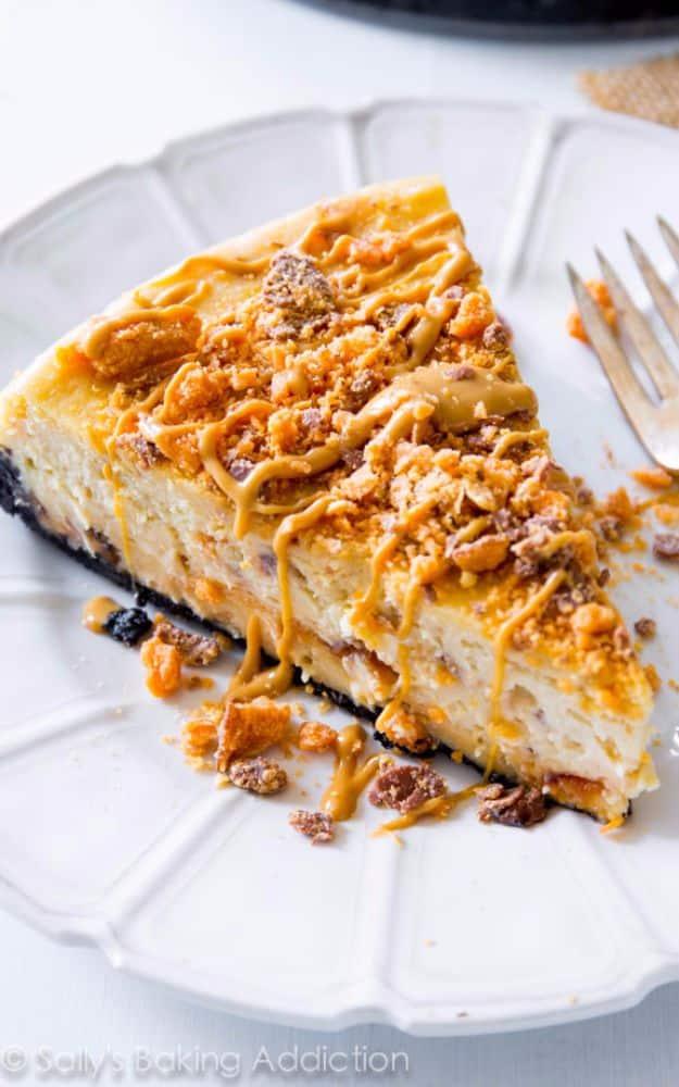 Peanut butter Butterfinger cheesecake slice with crushed candy bar pieces and peanut butter drizzle on top